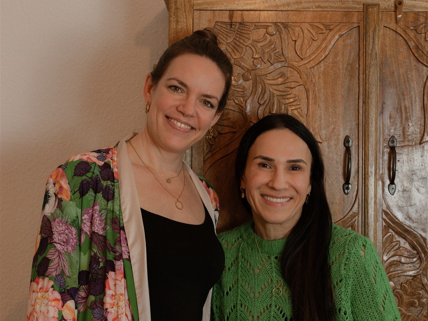 Steffi Mittenzwei und Arzu Dogan lächeln vor einem geschnitzten Holzschrank